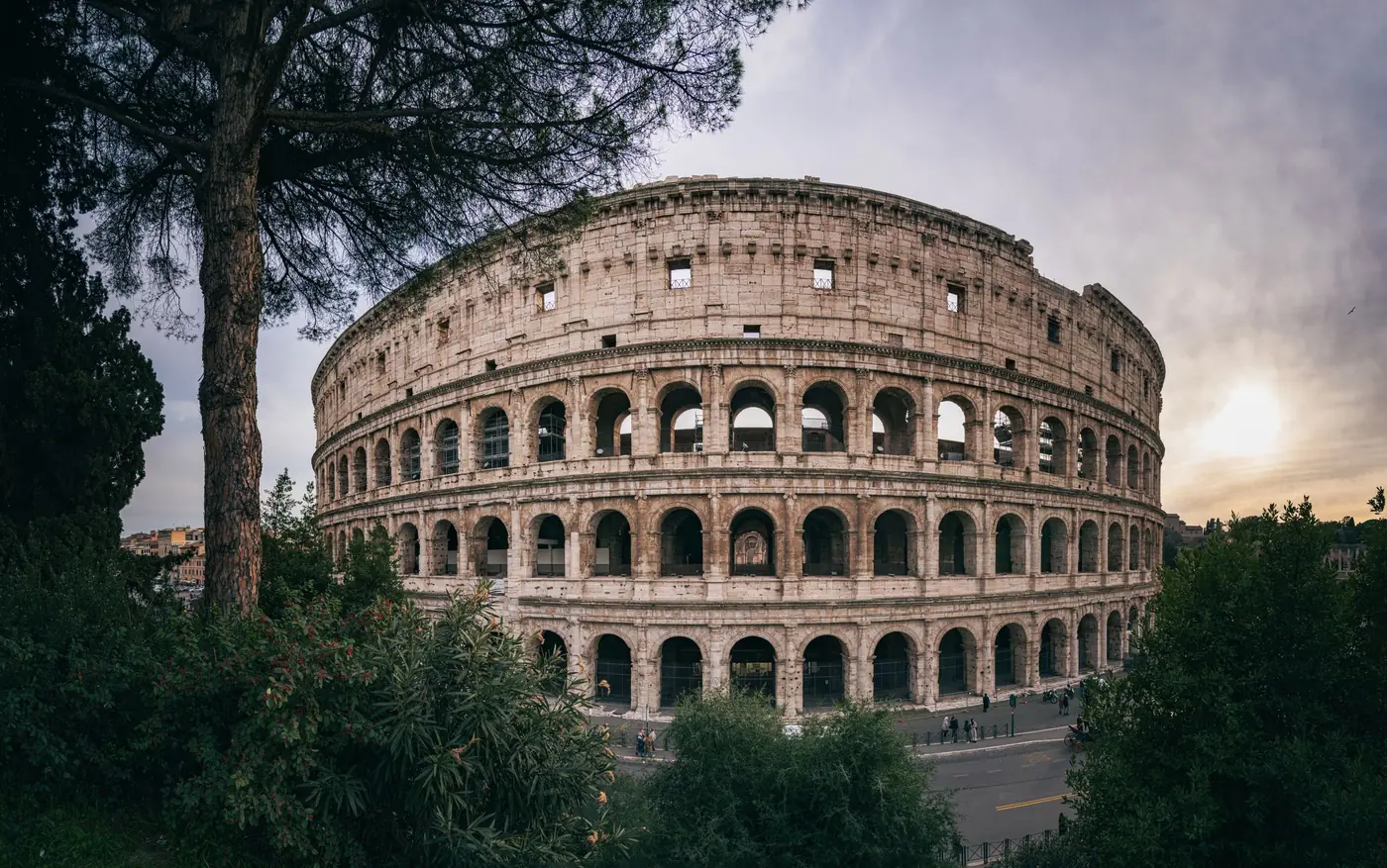 The Colosseum in Rome, Italy, framed by trees at sunset